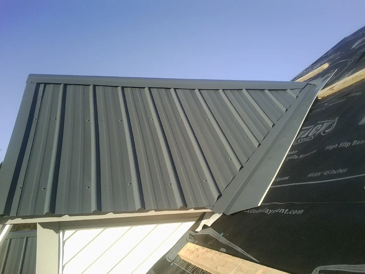 Gray metal roof panels going on over a garage gable in Beach Lake