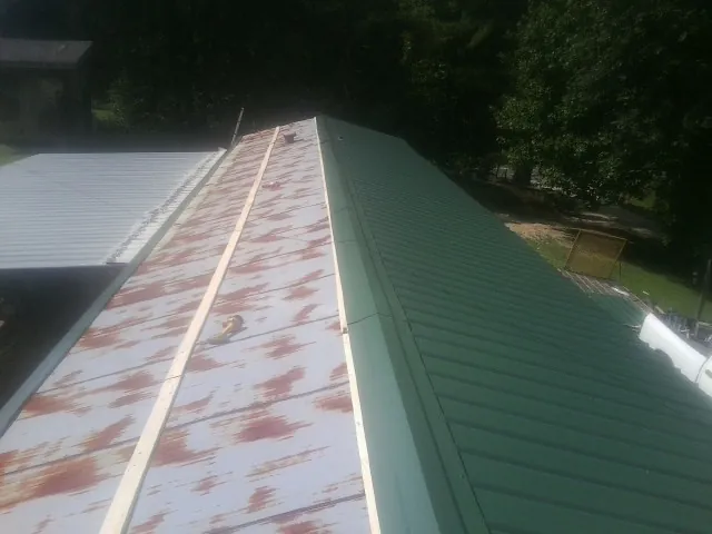 Old rusted panels beside newly installed green metal roofing — Wind Damage Roof Repair by Roofing Brothers in Beach Lake