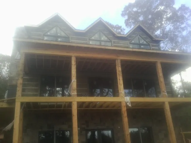 Dormers and porch framing on a large log home under construction — Roof Coating work by our crew in Beach Lake