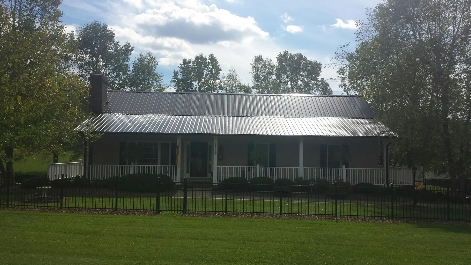 Gray metal roof on a brick ranch with a full width front porch — Gutter Guard Installation work by our crew in Beach Lake