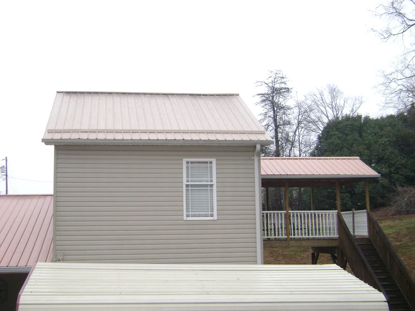 Tan metal roofs on a two story addition and attached porch, from a Roof Replacement job in Beach Lake