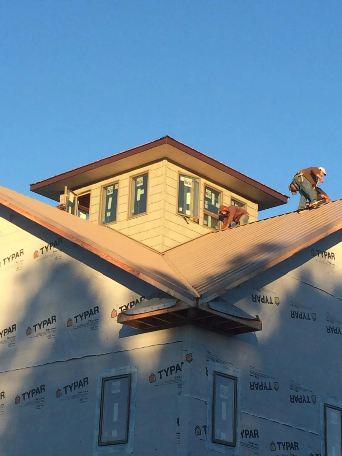 Roofers working around a rooftop cupola on a new metal roof at sunset — Roof Waterproofing in Beach Lake by Roofing Brothers